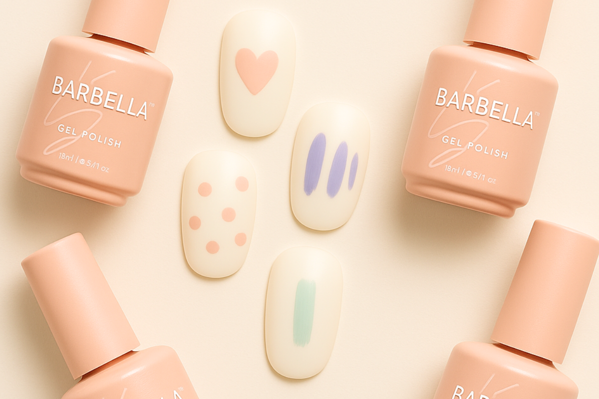 Peach BarBella Co. polish bottles around five cream nail tips painted with beginner designs: a pink heart, purple stripes, pink dots and pastel brush strokes.