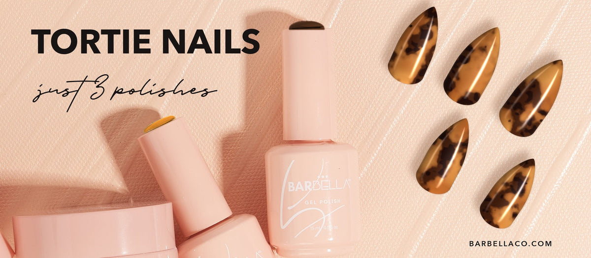 Five glossy amber and dark brown tortoiseshell stiletto nails beside peach BarBella Co. gel polish bottles. The fall 2026 tortie nail trend done at home with three vegan gel polishes.